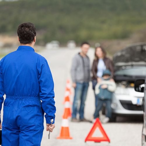 aubrey-towing-15 a man in blue overalls standing in front of a car with a child and a family